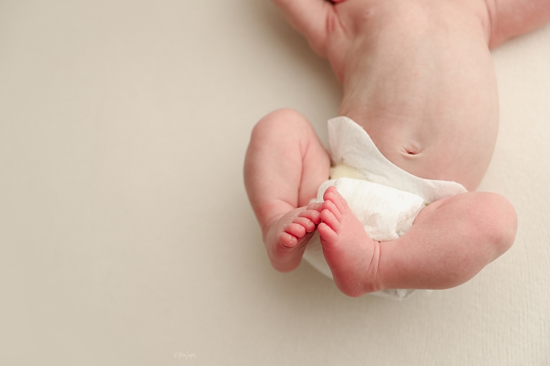 Newborn Photographer, a baby's feet and legs curl upward as baby lays down