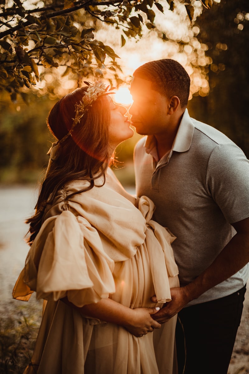 Fine Art Maternity Photographer, an expectant mother and father kiss at sunset before the lake