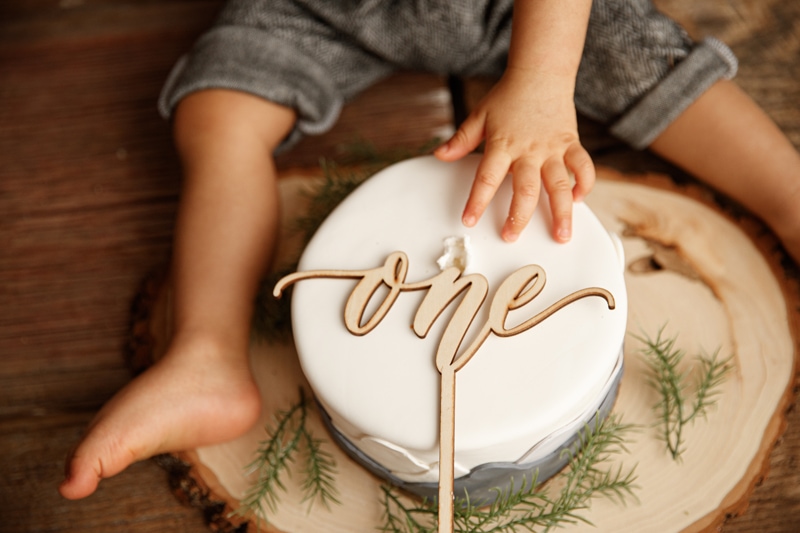Baby Photographer, baby's legs wrap around a cake that says one