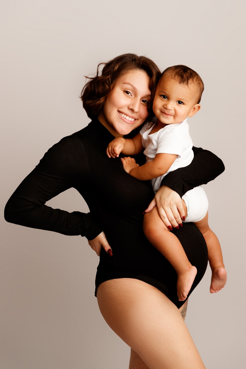 Fine Art Maternity Photographer, a pregnant mother holds her baby son, both with big smiles