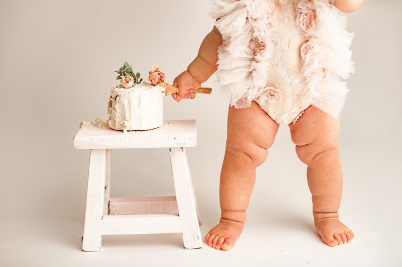 Baby Photographer, a baby girl with a wooden spoon, digs into her cake