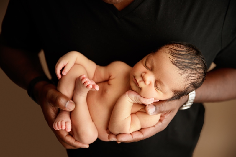 Newborn Photographer, a father's arm gently holds his napping  baby son