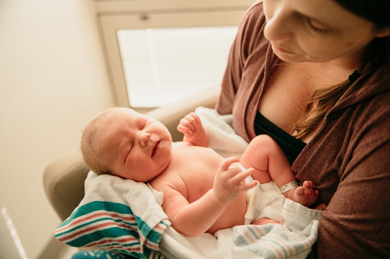 Birth Photographer, a young mother holds her baby in her arms