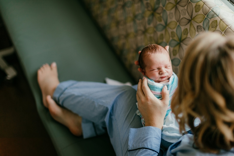Fresh 48 Photographer, Mother wears pajamas and admires her newborn baby in her arms