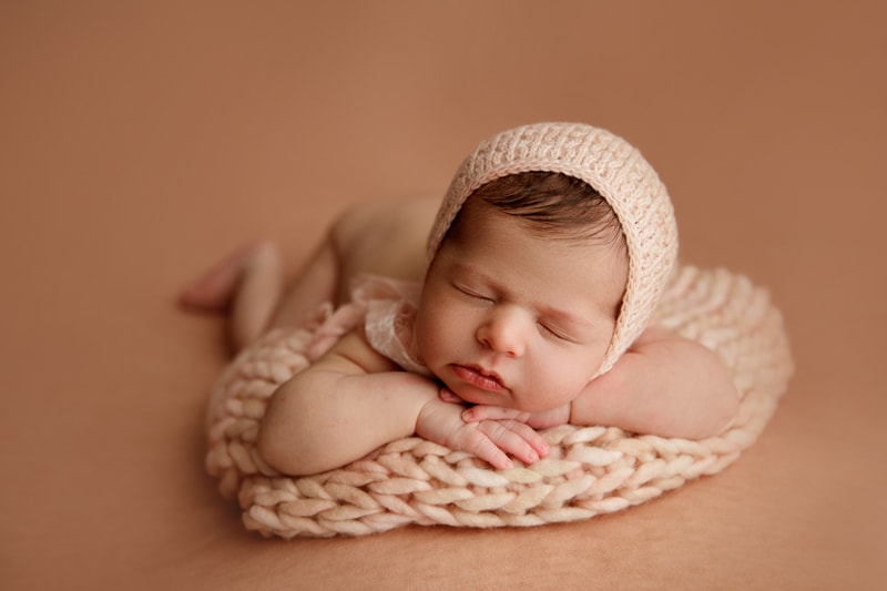Newborn Photographer, a baby lays on her little hands and lays on a crocheted blanket