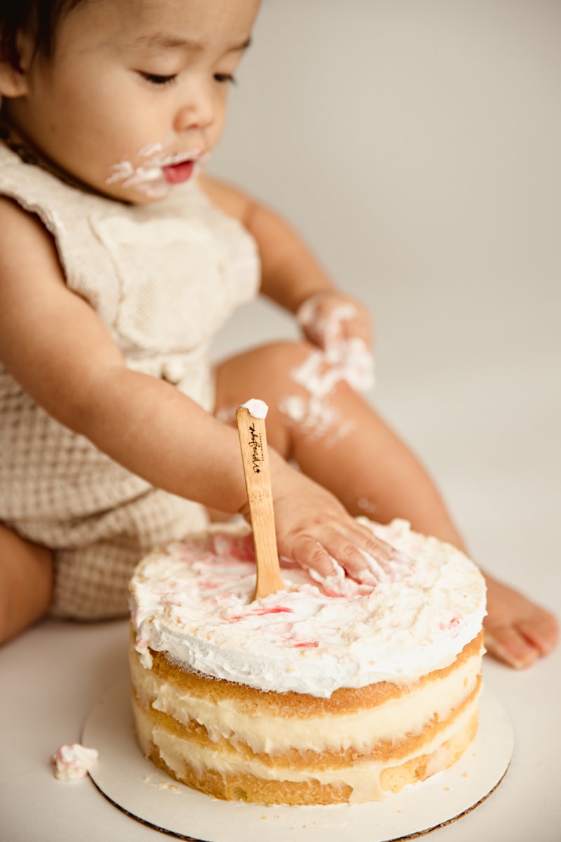 Baby Photographer, a little baby girl plays with her milestone cake