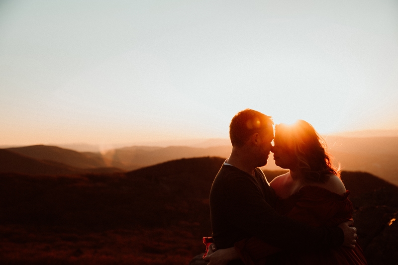 Family Photographer, a husband and wife draw close, nose-to-nose, on the hillside as the sun sets