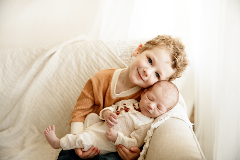 Newborn Photographer, older brother snuggles with his newborn baby younger brother