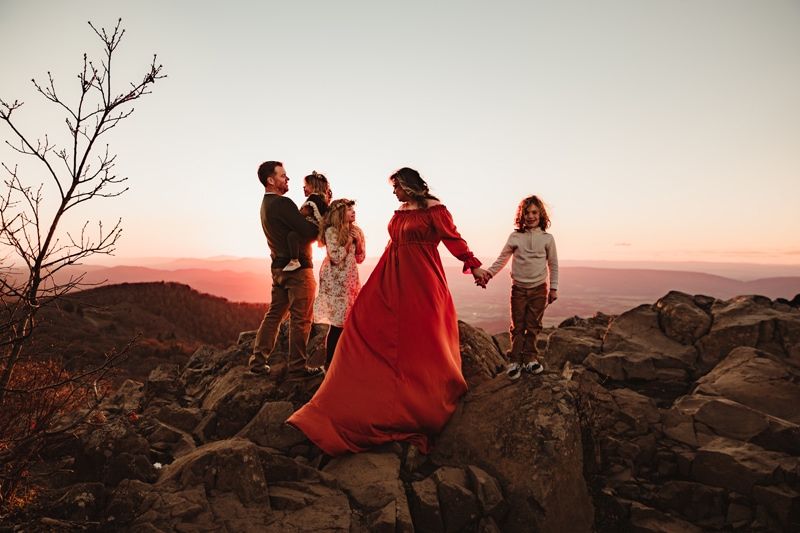 Family Photographer, a family walks on the rocks through the countryside as the sun sets