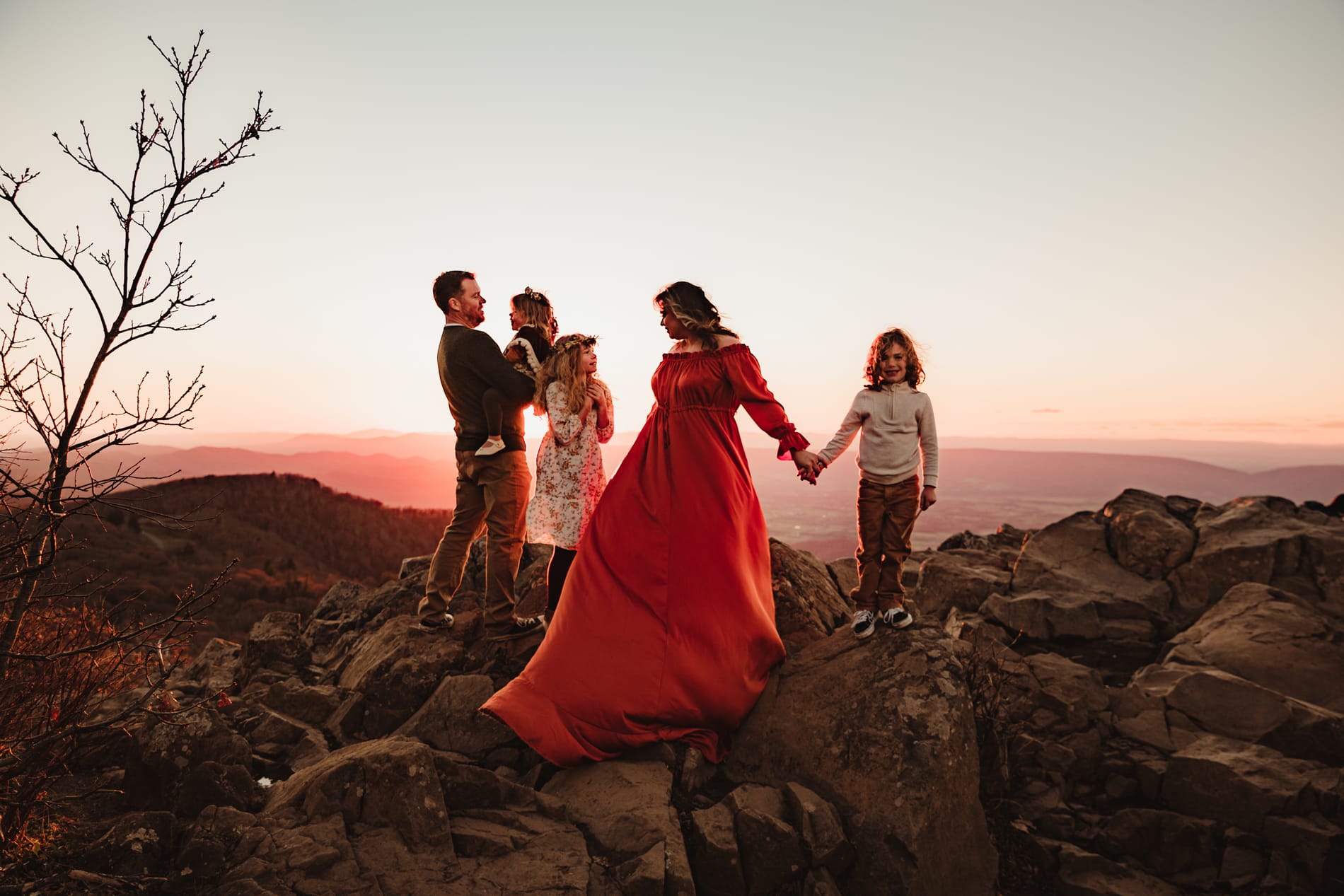 Family Photographer, a family of five stand on a rocky hillside summit admiring each other