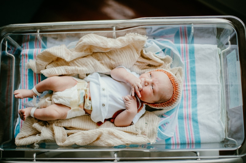 Fresh 48 Photographer, a newborn baby lays awake in a hospital bassinet