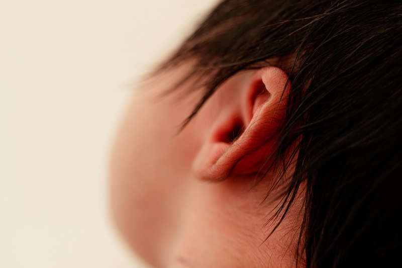 Newborn Photographer, a close-up of a little baby's ear, a full head of hair surrounds it