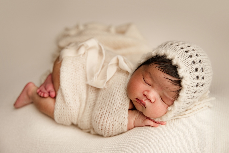 Newborn Photographer, a baby is bundled in a crochet blanket and naps