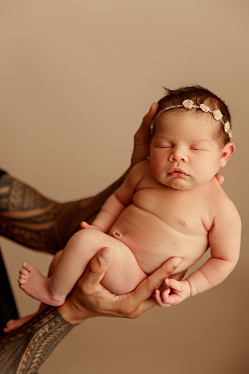 Newborn Photographer, tattooed arms of a mother hold her newborn baby girl
