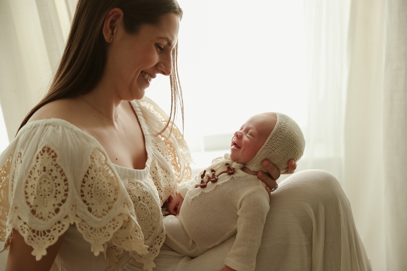 Lifestyle Photographer, a new mother holds her baby, the baby looks to be smiling