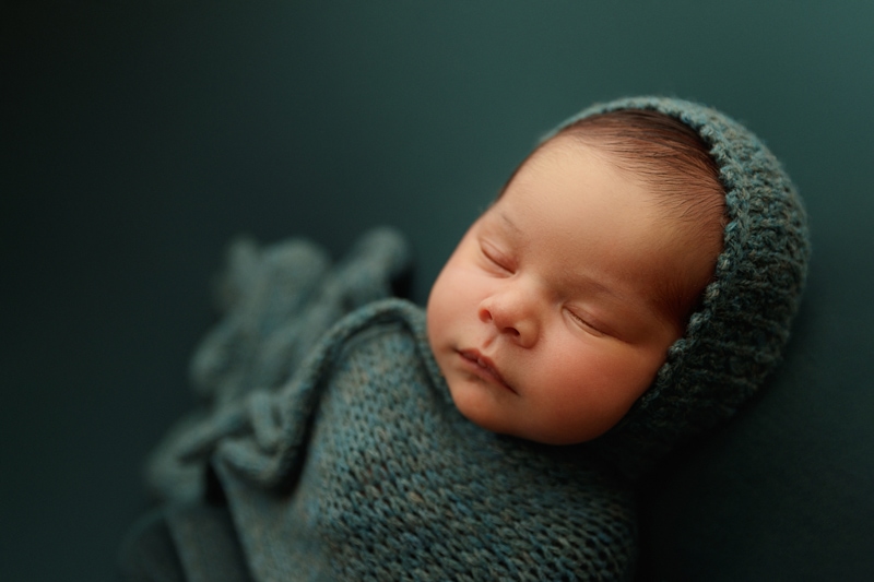 Newborn Photographer, a baby lays sleeping in knit onesie