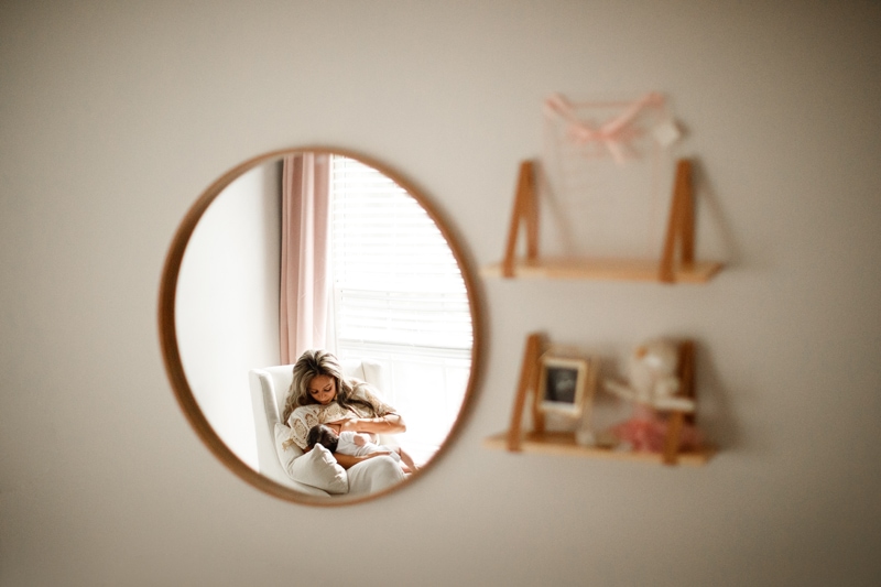 Lifestyle Photographer, in a mirror's reflection, a mother is breastfeeding her baby