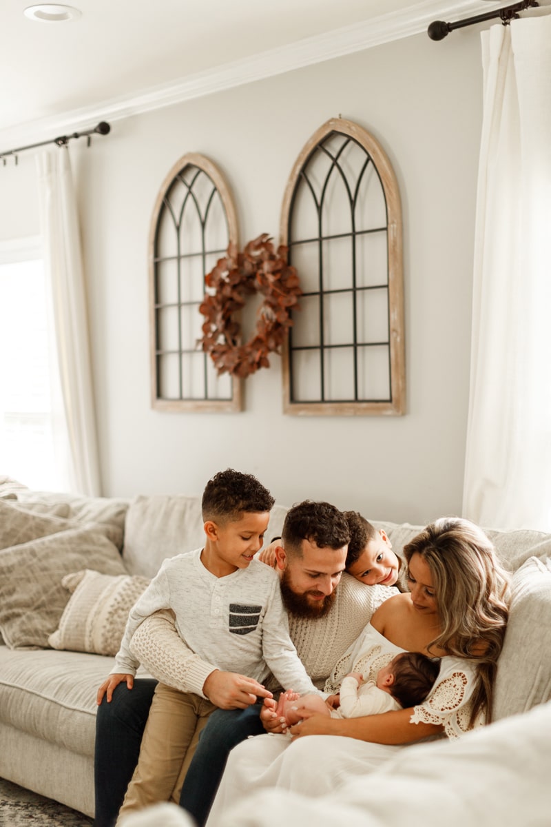Lifestyle Photographer, family looks on at newborn baby addition in their living room