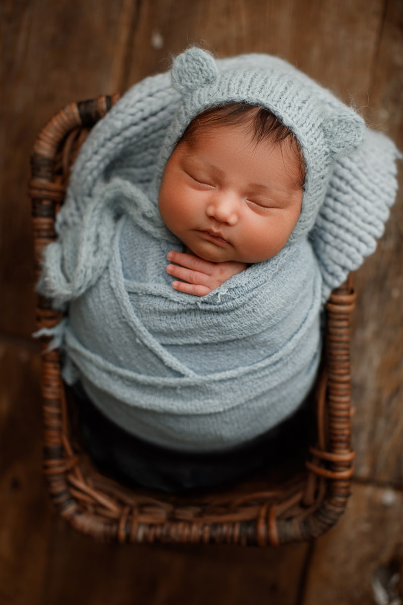 Newborn Photographer, a little baby lays in a basket swaddled in blankets