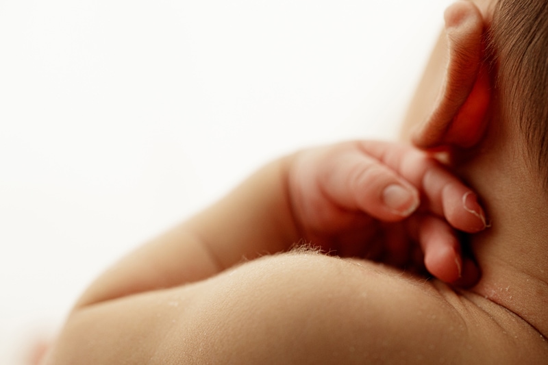 Newborn Photographer, a babys hands rest on his shoulders with details of little nails and baby fuzz
