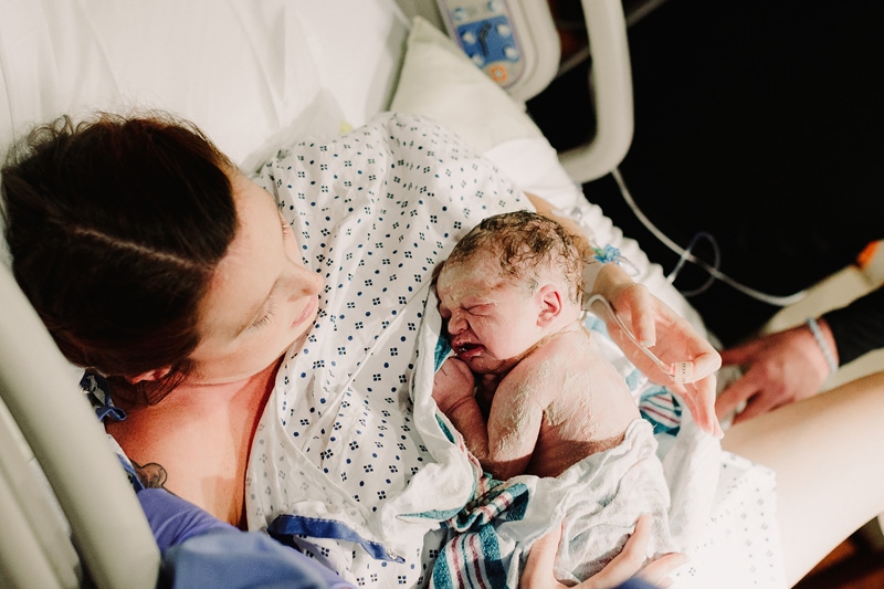 Birth Photographer, a mother holds her newborn baby immediately after birth