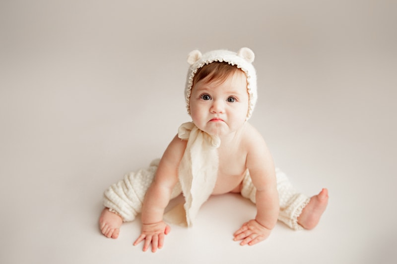 Baby Photographer, little girl with bear cub cap has a frown on her face