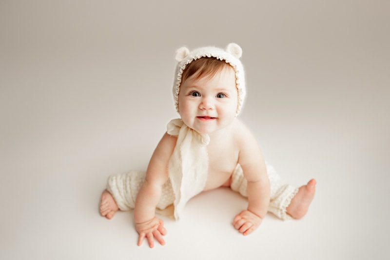 Baby Photographer, a little girl wears a cap with bear cub ears and knit stockings