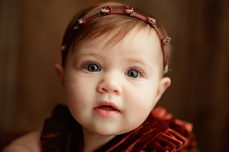 Baby Photographer, baby girl wears a headband and velvet dress