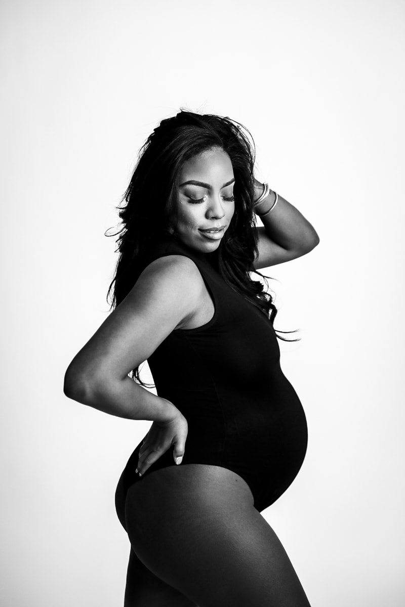 Fine Art Maternity Photographer, an expecting woman places her hand on her hip as she celebrates her baby bump