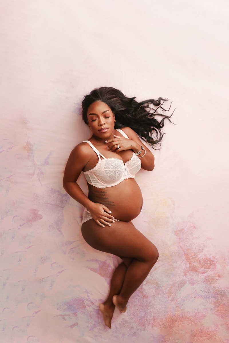 Fine Art Maternity Photographer, a mother to be lays down in her underwear, her pregnant belly is shown, she is confident