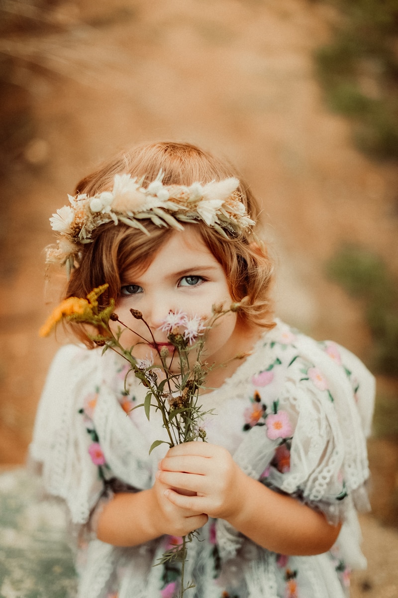 Family Photographer, a little girl wears a flower wreath and smells wildflowers