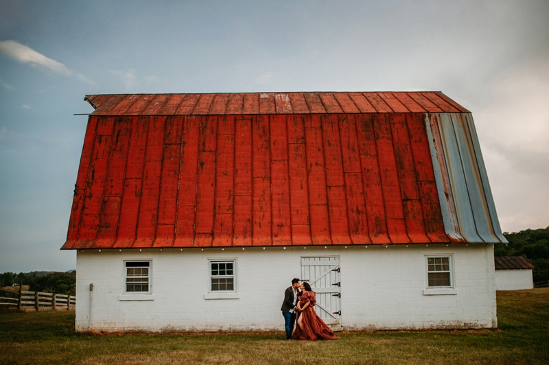 Fine Art Maternity Photographer, a pregnant mom-to-be kisses her husband before a country barn
