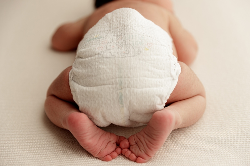 Newborn Photographer, baby lays sleeping, feet tucked behind little diaper