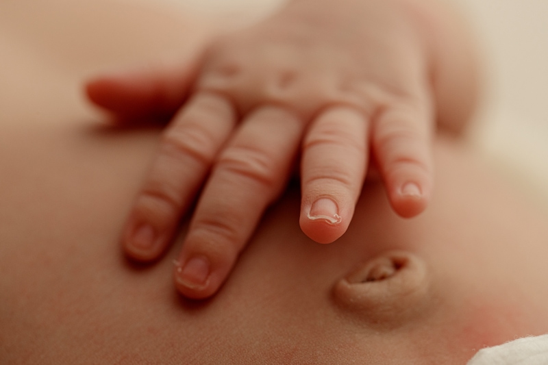 Newborn Photographer, baby hands lay on belly over belly button
