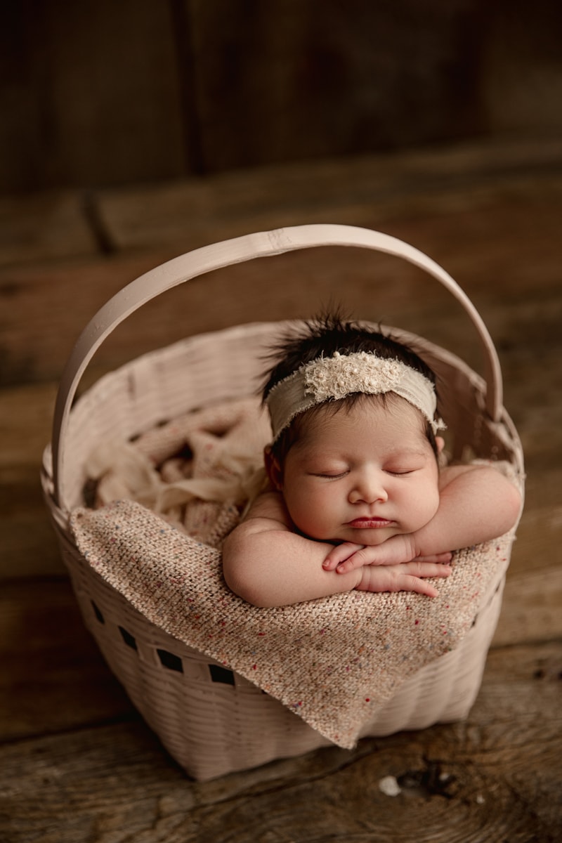Newborn Photographer, Baby girl wears headband and sleeps in a basket