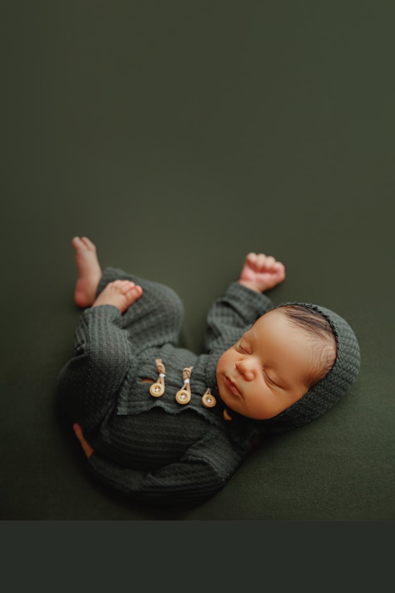 Newborn Photographer, baby lays sleeping with knit onesie on