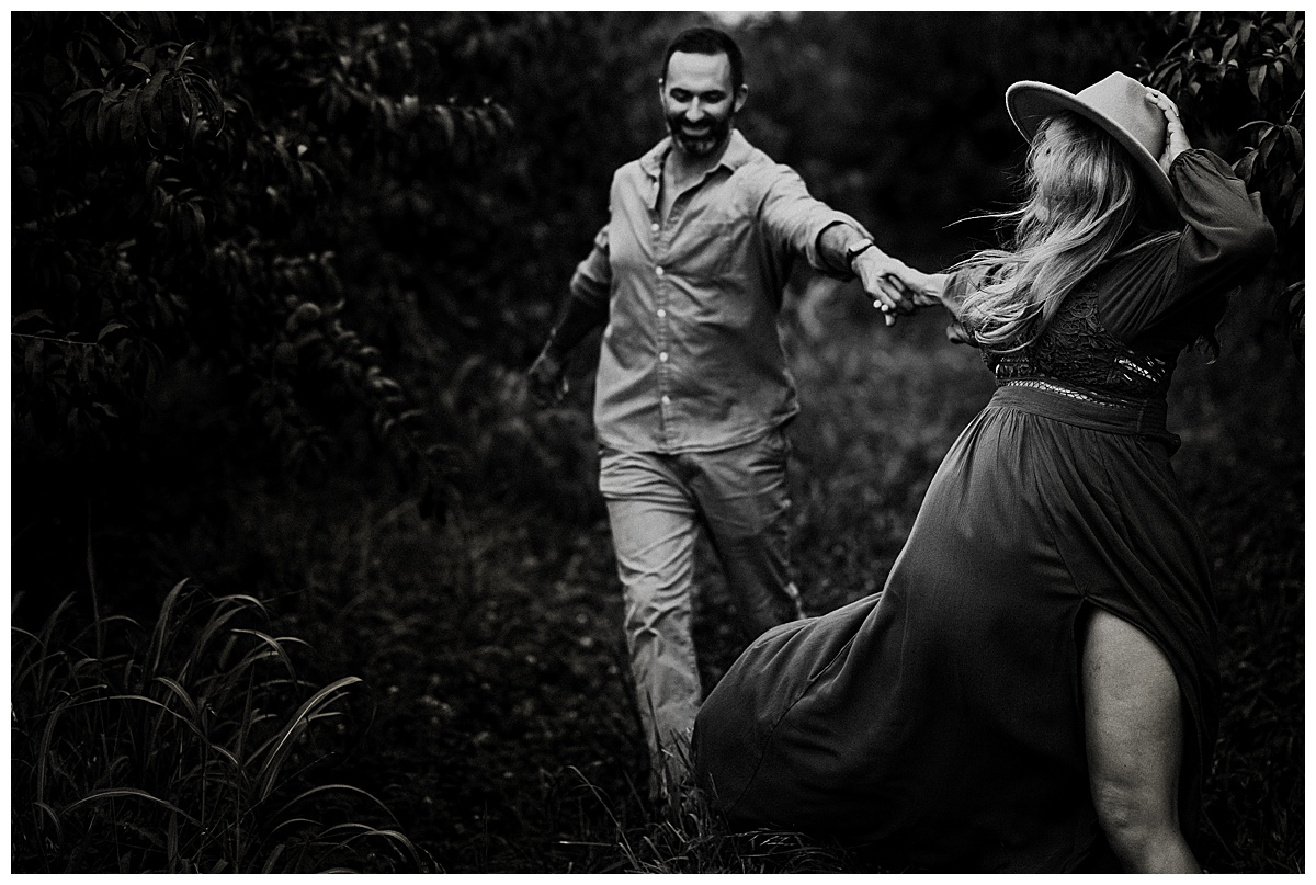 Woman leading man through field during Great County Farms Maternity Session