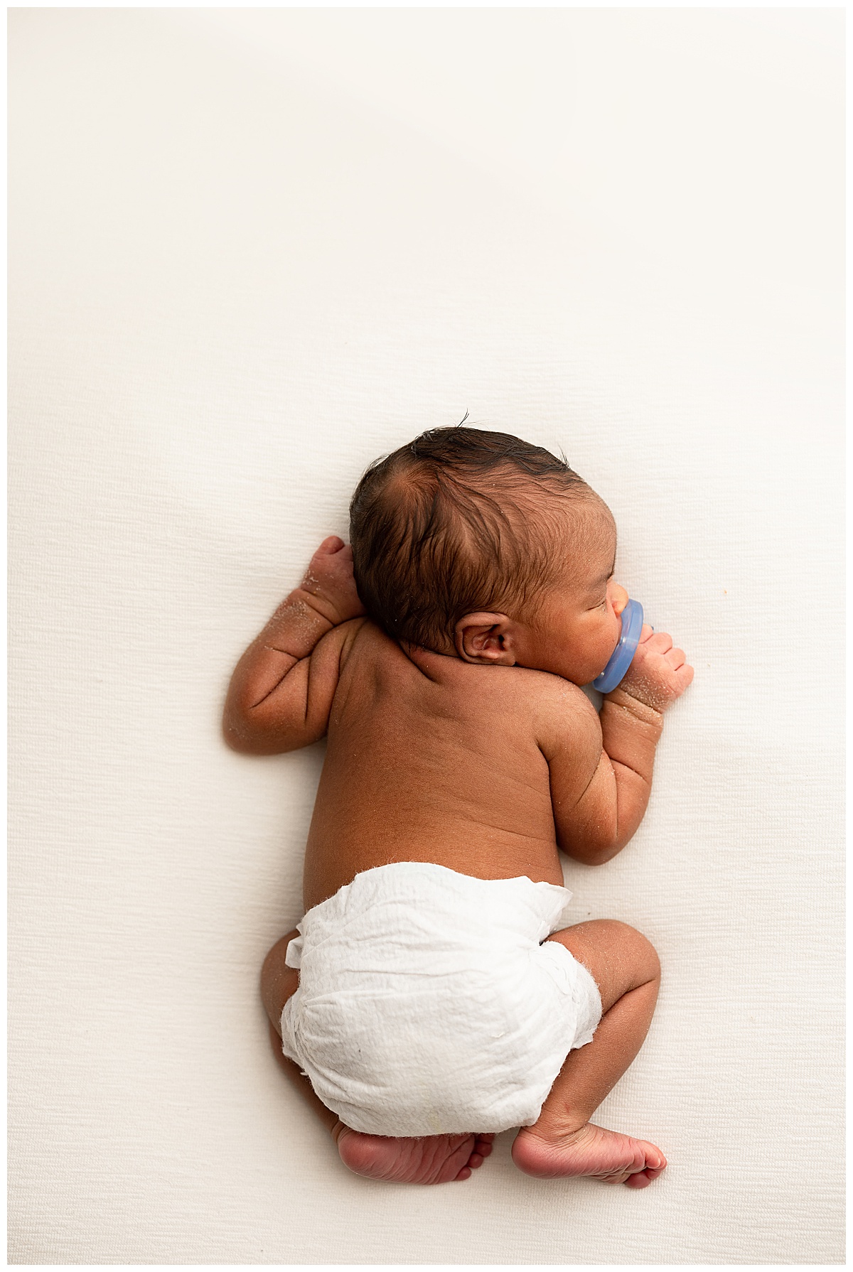 Baby lays on belly with pacifier for Occoquan, VA Newborn Studio