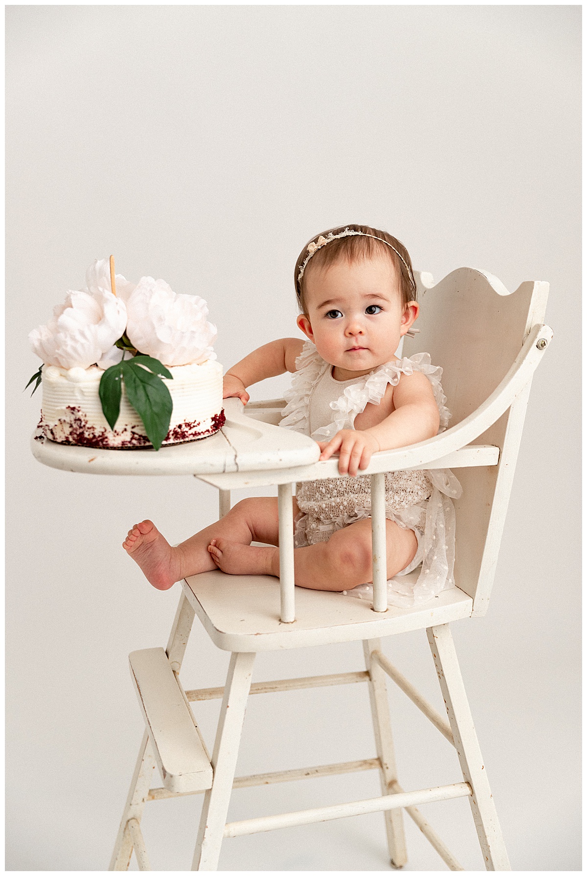Little girl is holding high chair for First Birthday Cake Smash
