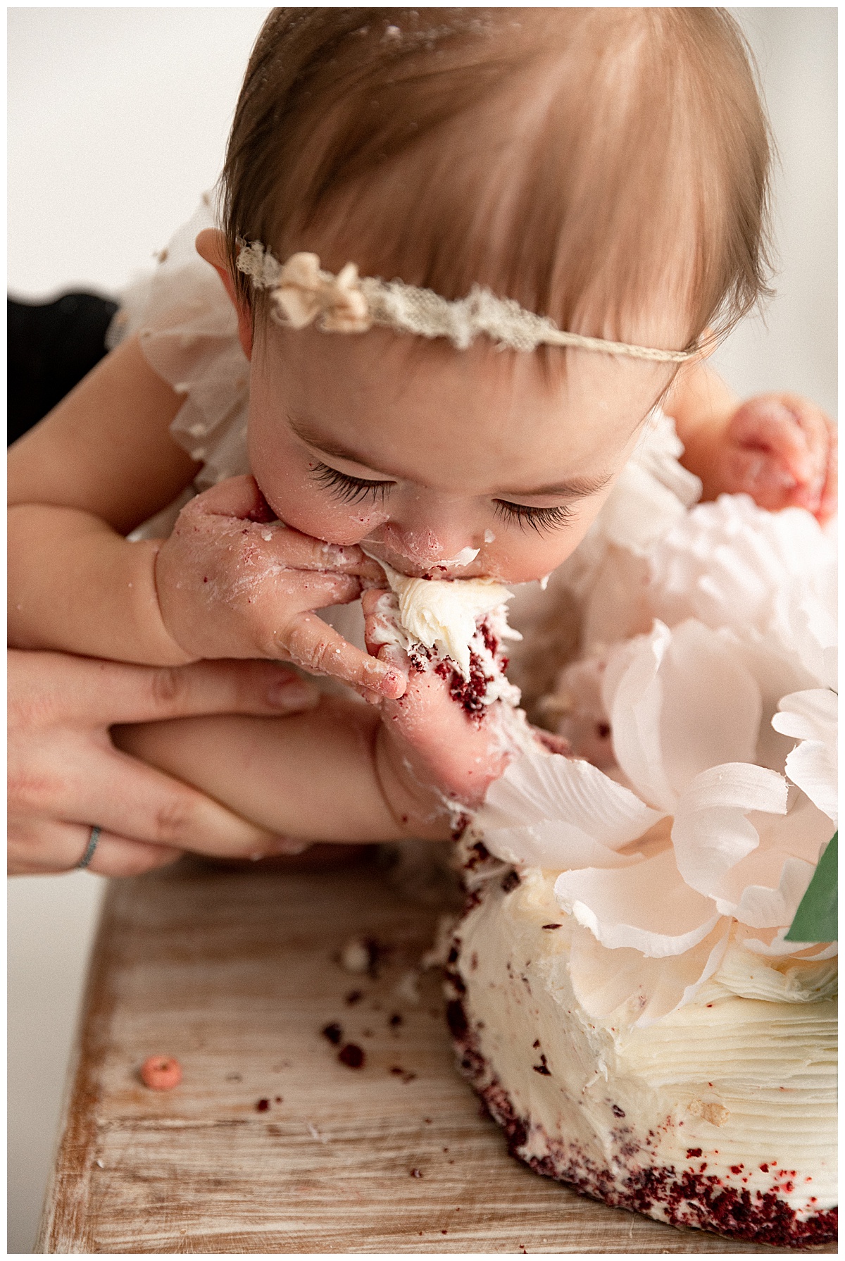 Baby licking toe with cake for First Birthday Cake Smash