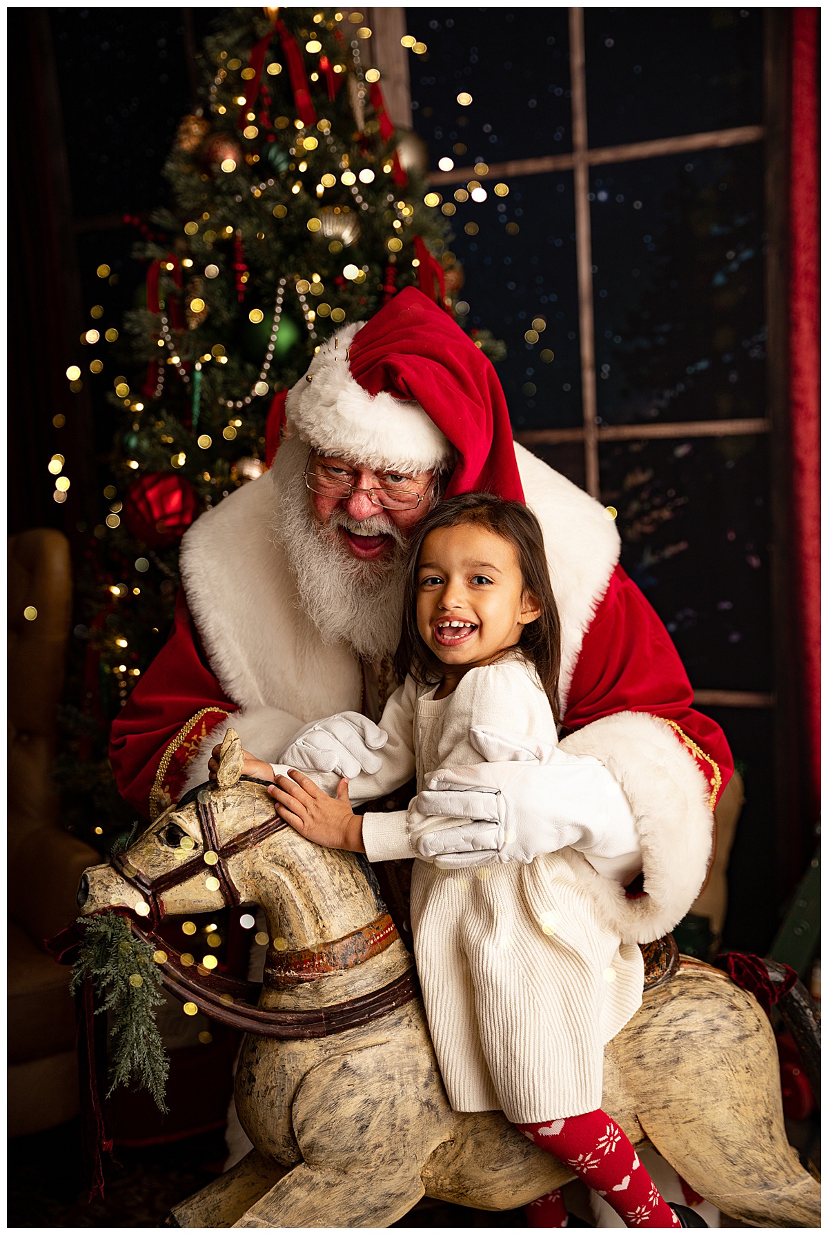 Girl smiles with Santa on rocking horse for Norma Fayak Photography