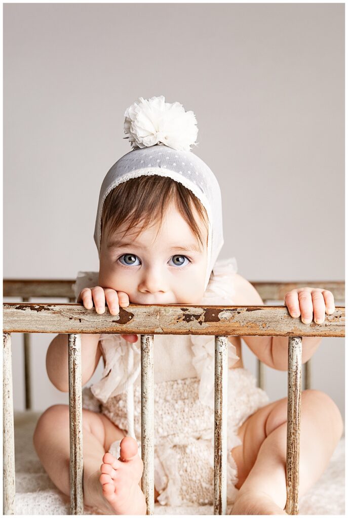Little one chews on crib for First Birthday Milestone Portraits