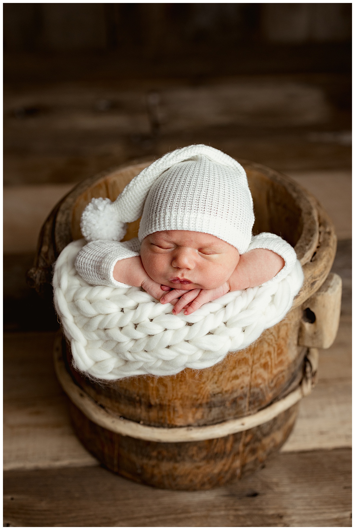 Infant sits on wooden basket for Intimate Studio Newborn Session