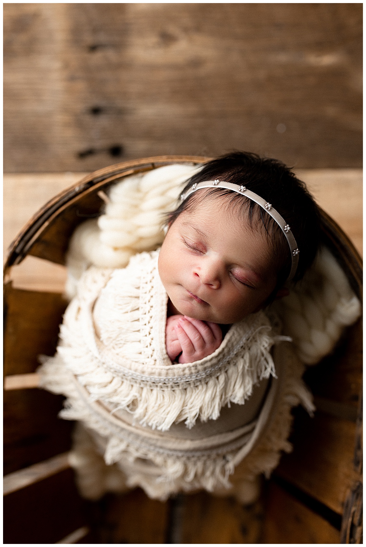 Newborn sits on basket wrapped in boho blanket for Norma Fayak Photography