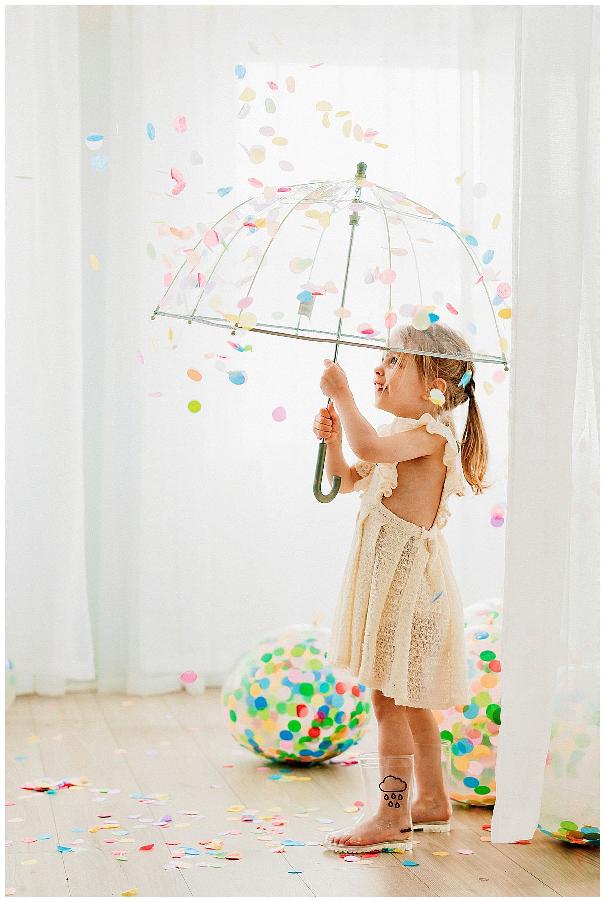 Little girl holds umbrella as confetti falls for her Birthday Session In The Studio 