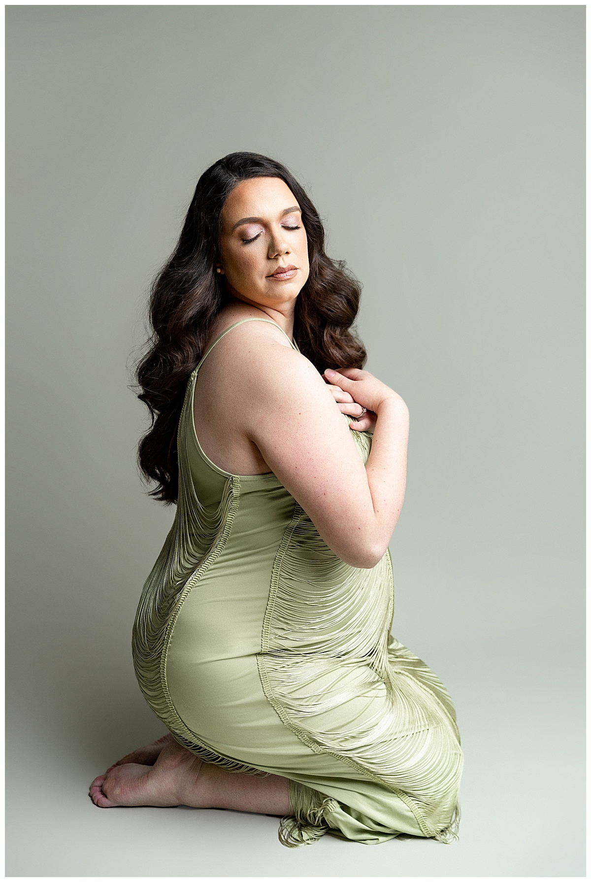 Woman sits on the grown in green gown for her Full Fine Art Maternity Session