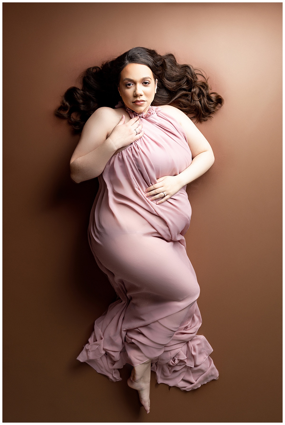 Mama to be lays down in pink gown for her Full Fine Art Maternity Session