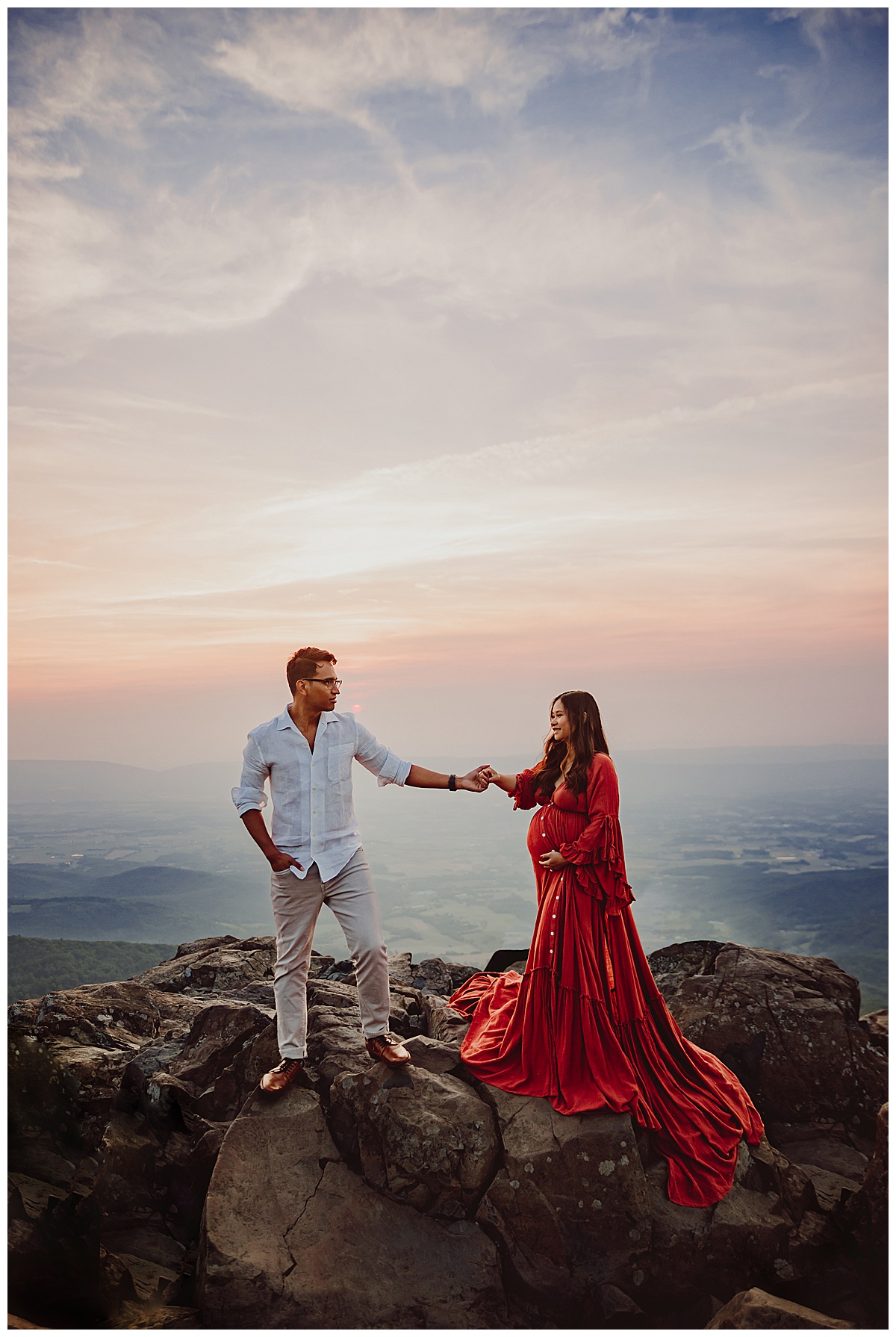 Man leads woman up the rock for Shenandoah Mountains Adventurous Maternity Session