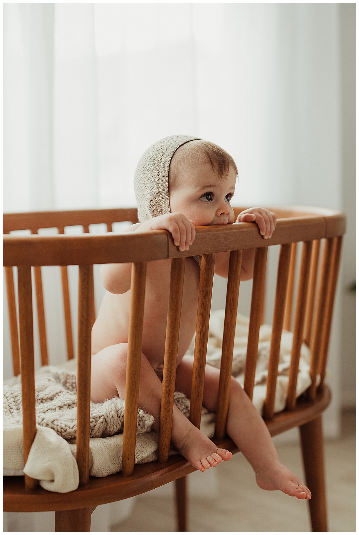 Little baby sits on the crib for Unposed Lifestyle Family Photos