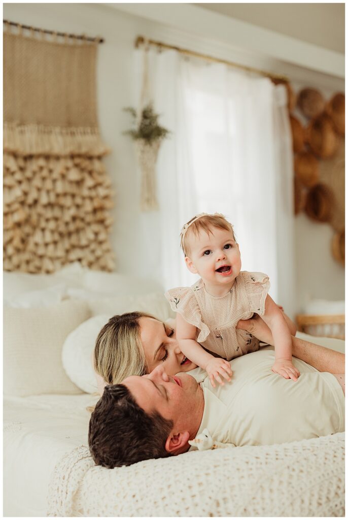 Baby sits on parents for Unposed Lifestyle Family Photos
